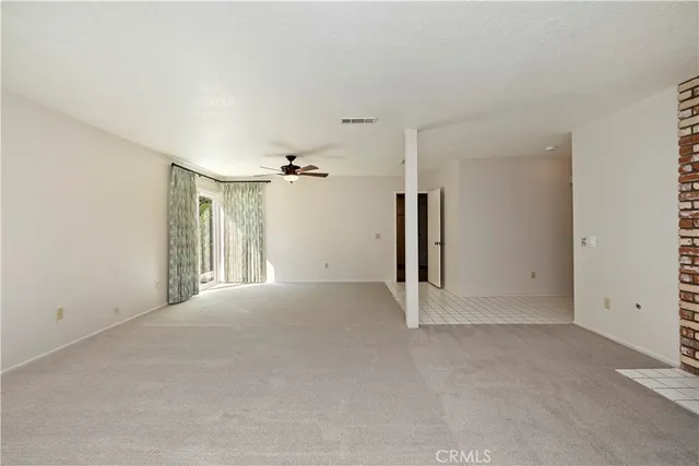 an empty room with wooden floor and ceiling fan