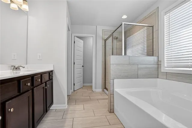 a spacious bathroom with a tub sink and mirror