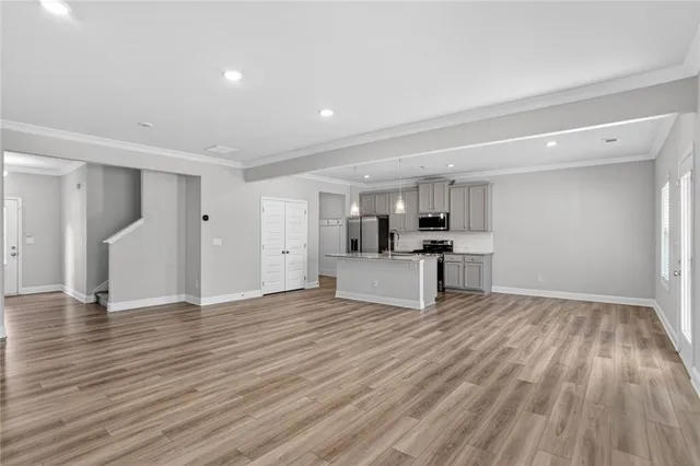 a view of kitchen with empty room and wooden floor