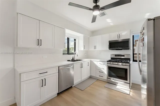 a kitchen with white cabinets and stainless steel appliances