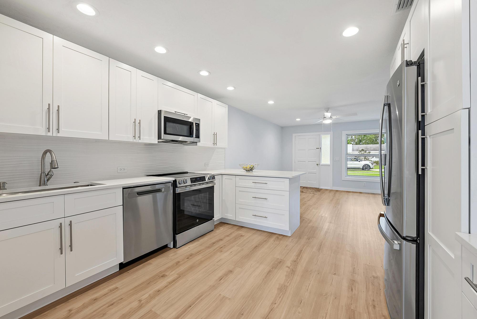 200 Anglers Circle Jupiter, FL 33458 - Photo 4 of 19 a kitchen with stainless steel appliances kitchen island granite countertop a stove a sink and white cabinets