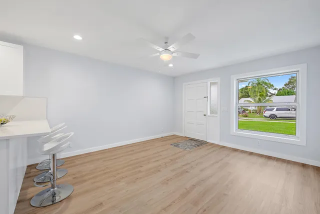 a view of an empty room with a window and wooden floor