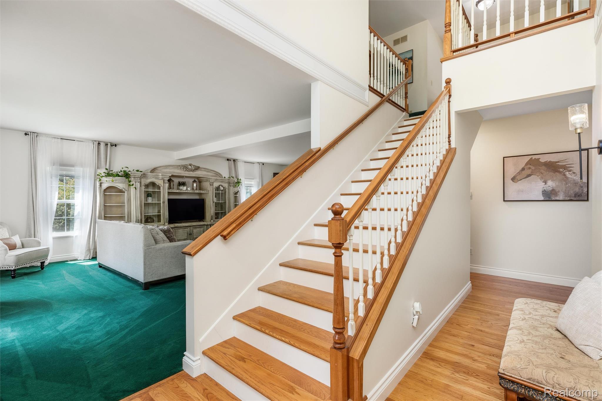 21280 Merriman Road New Boston, MI 48164 - Photo 13 of 65 Open-concept living area with a built-in entertainment center, a grand staircase featuring wood treads and handrails, and a two-story entryway