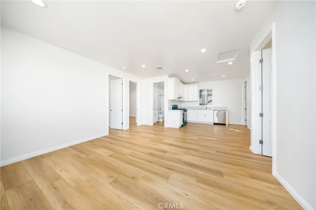 a view of kitchen and empty room with wooden floor