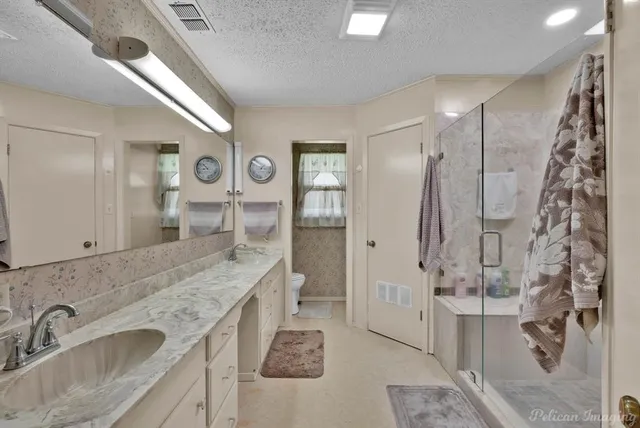 a bathroom with a granite countertop sink a mirror and shower