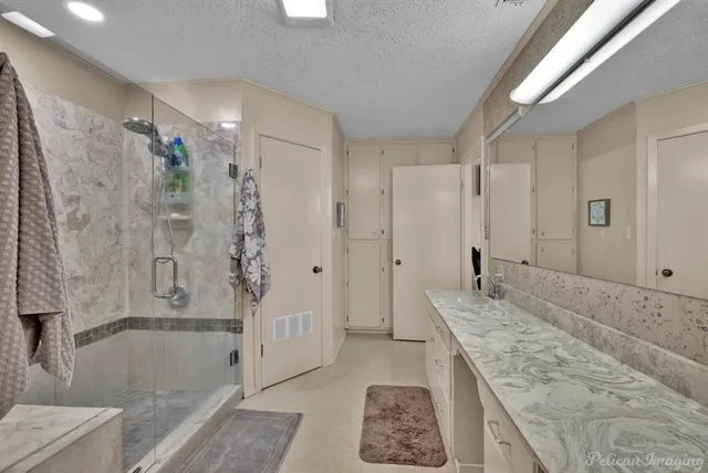a bathroom with a granite countertop sink a mirror a bathtub and shower