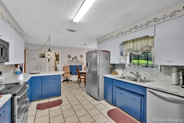 a kitchen with a sink a stove a refrigerator cabinets and dining table