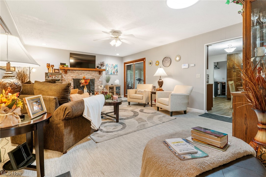 Carpeted family room with a fireplace and ceiling fan