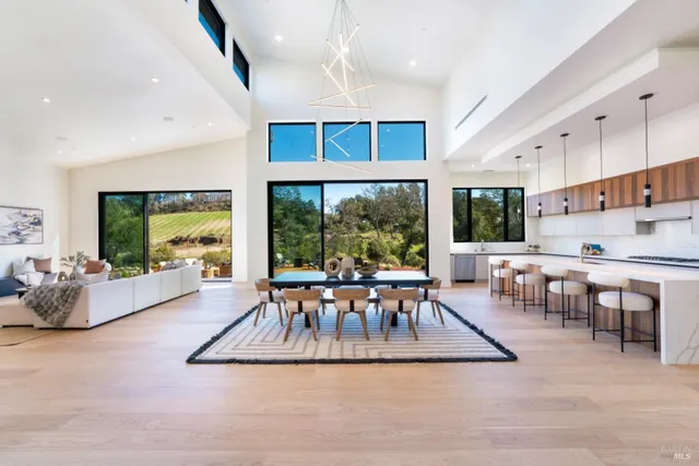a living room with furniture a large window and a dining table