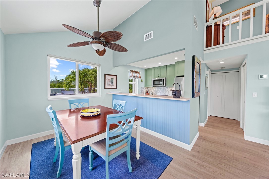 1649 Sand Castle Road Sanibel, FL 33957 - Photo 8 of 34 a dining room with wooden floor a chandelier fan a wooden table and chairs