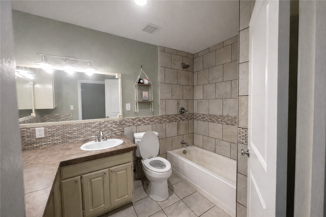 4005 Ridge Trail Robstown, TX 78380 - Photo 14 of 20 a bathroom with a granite countertop toilet a sink and a bathtub