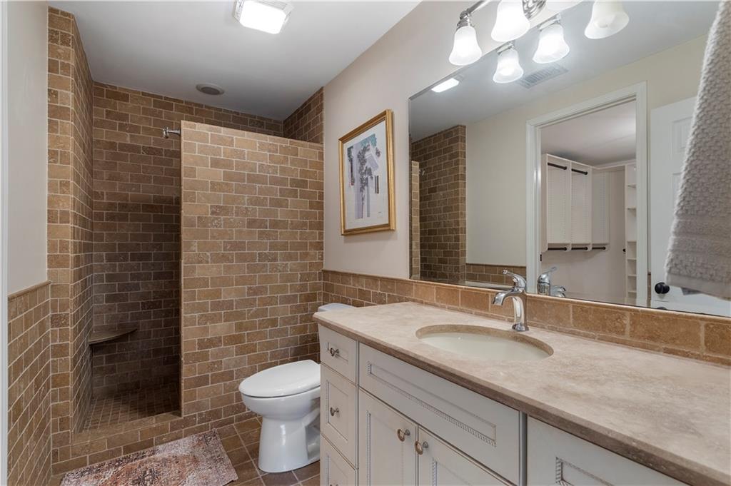 1174 Bowerie Chase Powder Springs, GA 30127 - Photo 42 of 70 a bathroom with a granite countertop toilet a sink a mirror and shower