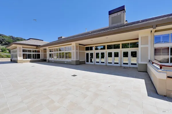 a view of a white building with large windows and a yard