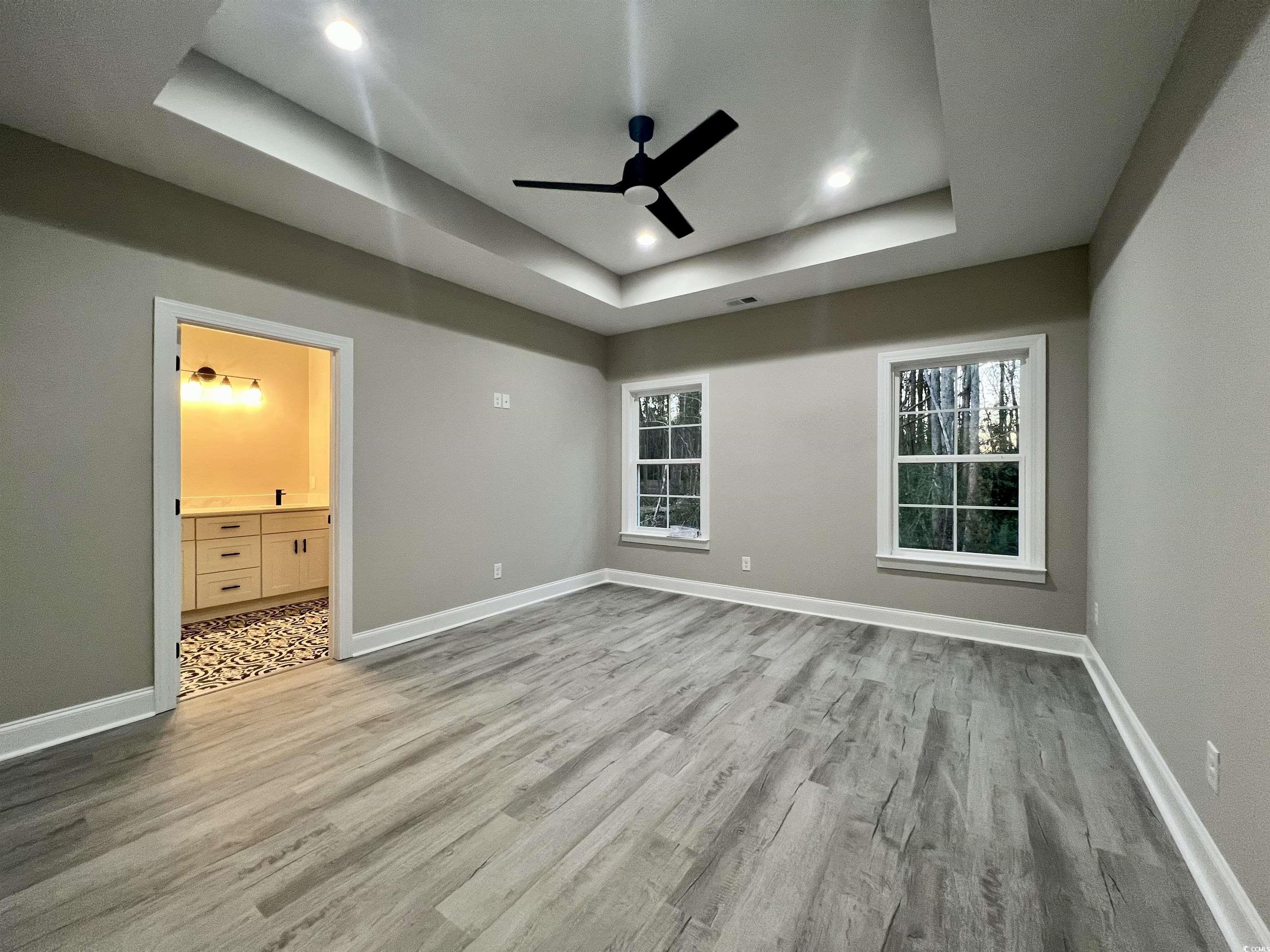 1107 Highway 9 Business Loris, SC 29569 - Photo 21 of 33 Unfurnished bedroom with light hardwood / wood-style flooring, ensuite bath, ceiling fan, and a tray ceiling