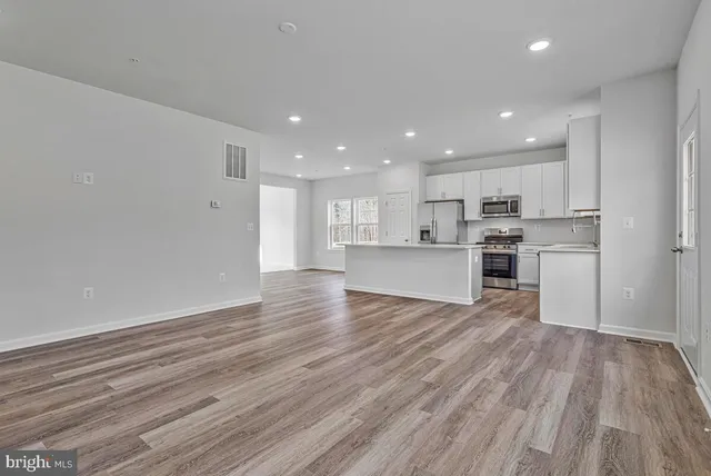 a view of an empty room with wooden floor and windows