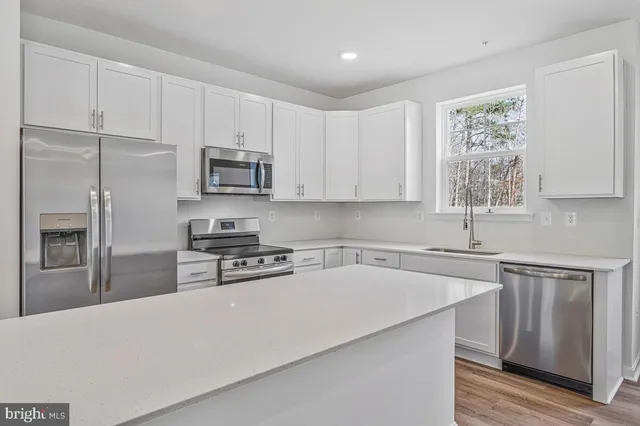 a kitchen with stainless steel appliances white cabinets a sink a stove a refrigerator and microwave