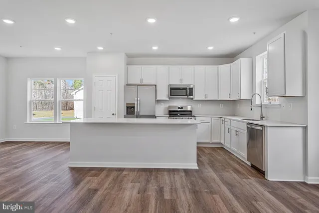 a large kitchen with a sink and dishwasher a stove top oven with wooden floor