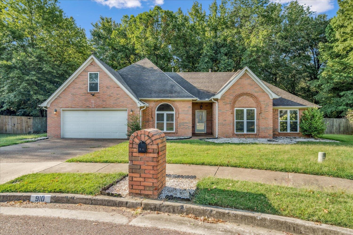 View of front of house featuring a shingled roof, brick siding, driveway, and an attached garage