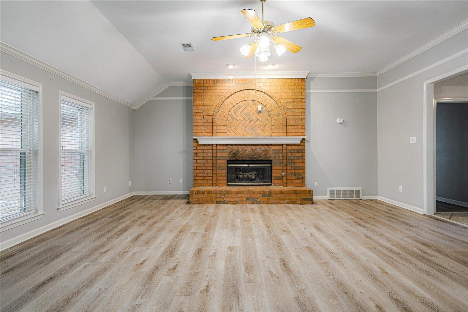 910 Sugar Cove Collierville, TN 38017 - Photo 6 of 32 Unfurnished living room featuring lofted ceiling, light wood-type flooring, ceiling fan, a fireplace, and crown molding