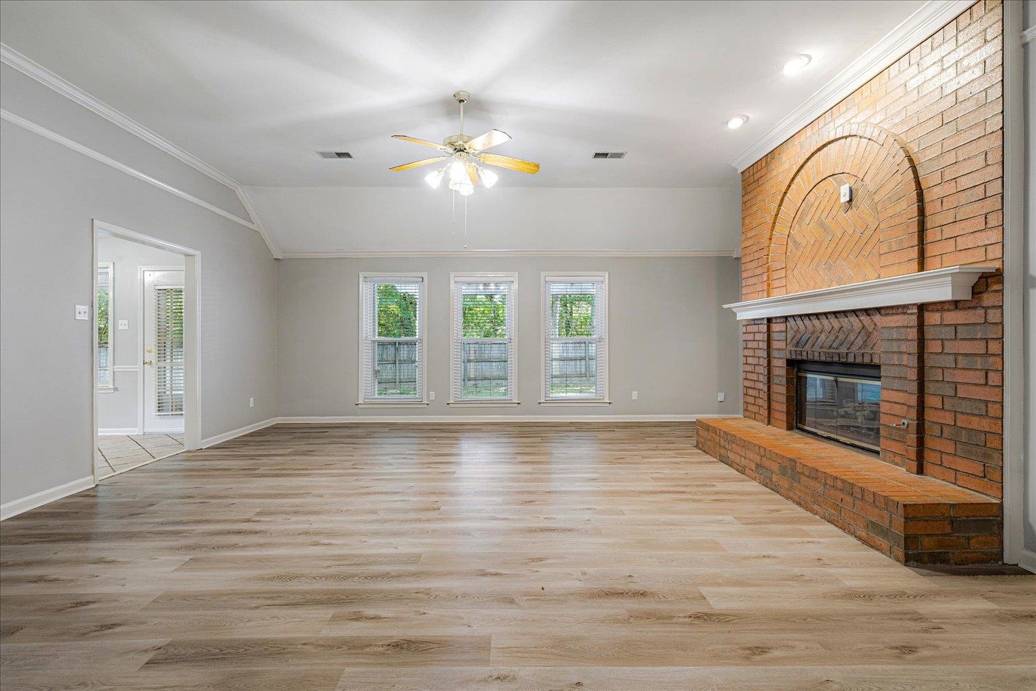 910 Sugar Cove Collierville, TN 38017 - Photo 7 of 32 Unfurnished living room with light wood finished floors, crown molding, ceiling fan, a brick fireplace, and recessed lighting