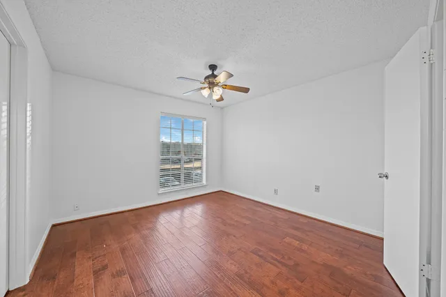 a view of an empty room with a window and wooden floor