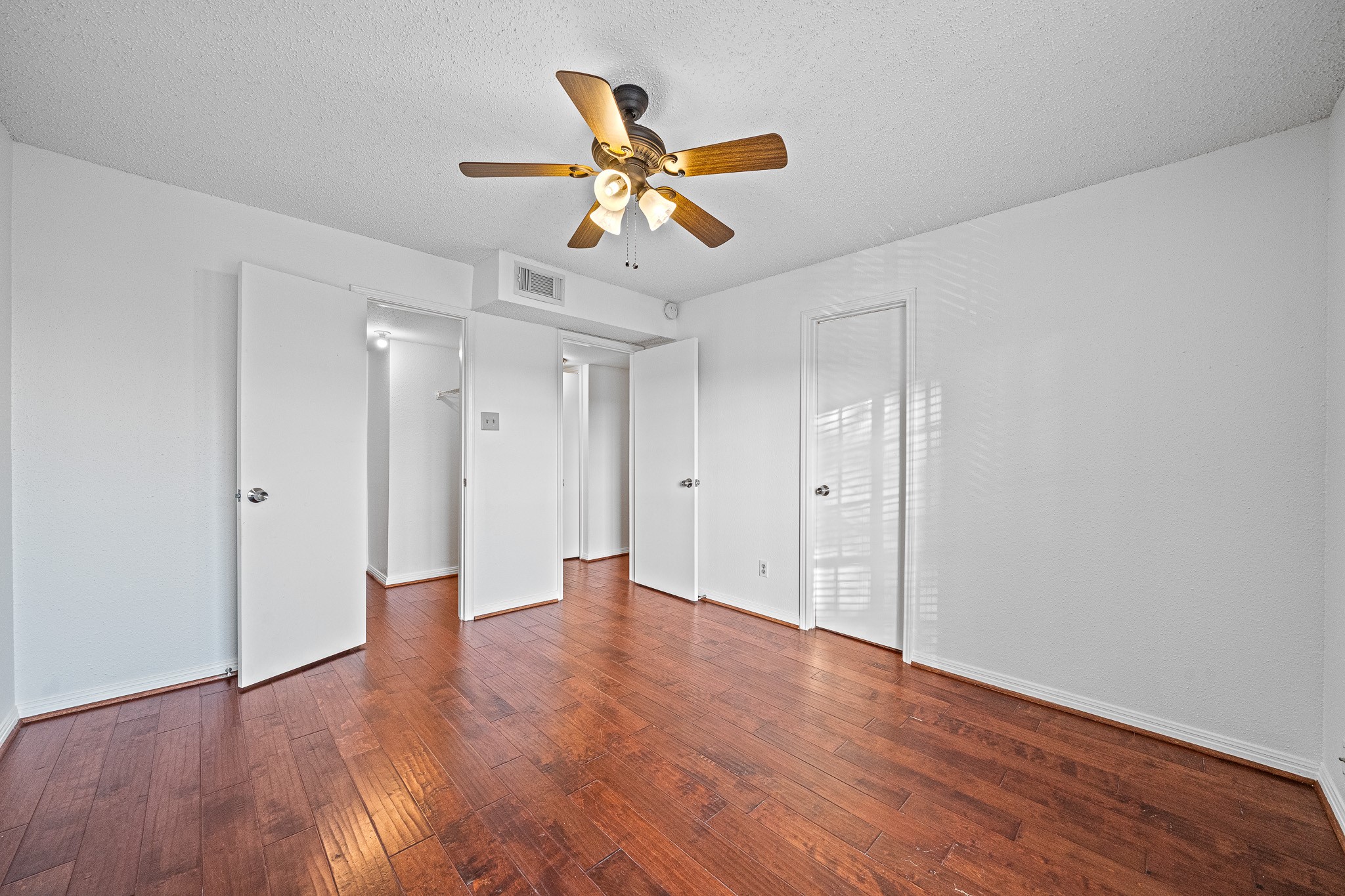12100 Overbrook Lane, Unit 17D Houston, TX 77077 - Photo 13 of 22 a view of an empty room with wooden floor and a ceiling fan