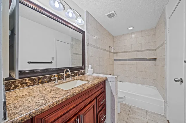 a bathroom with a granite countertop sink a mirror and a bathtub
