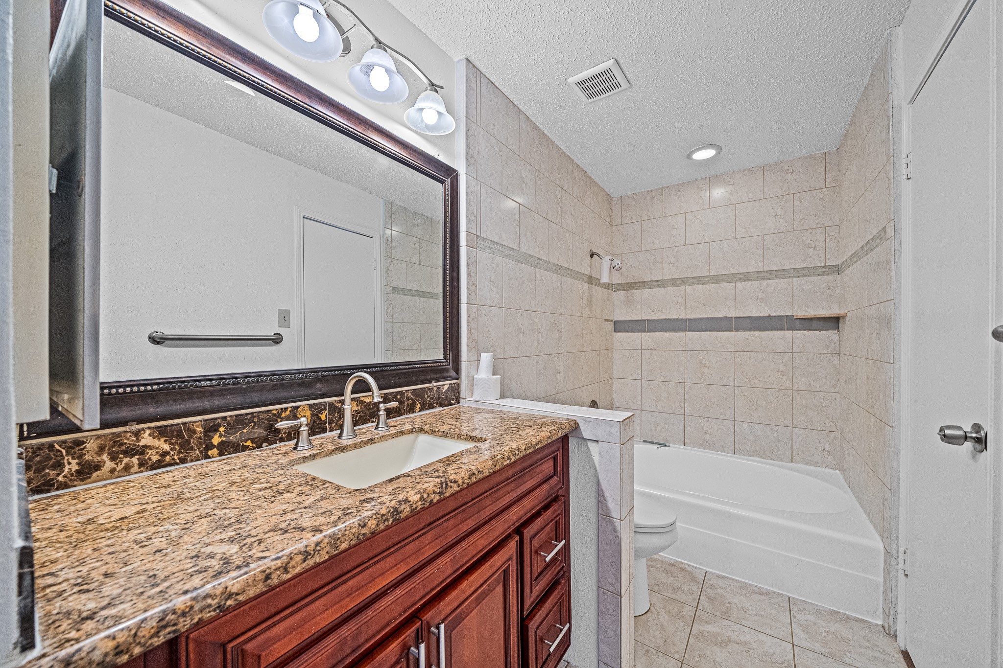 12100 Overbrook Lane, Unit 17D Houston, TX 77077 - Photo 15 of 22 a bathroom with a granite countertop sink a mirror and a bathtub