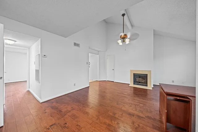 a view of an empty room with wooden floor and a fireplace