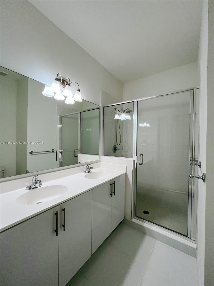 15650 Southwest 136th Street, Unit 218 Miami, FL 33196 - Photo 13 of 25 a bathroom with a double vanity sink mirror and shower
