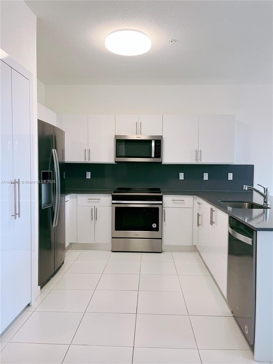 15650 Southwest 136th Street, Unit 218 Miami, FL 33196 - Photo 3 of 25 a kitchen with stainless steel appliances a stove a sink and a microwave