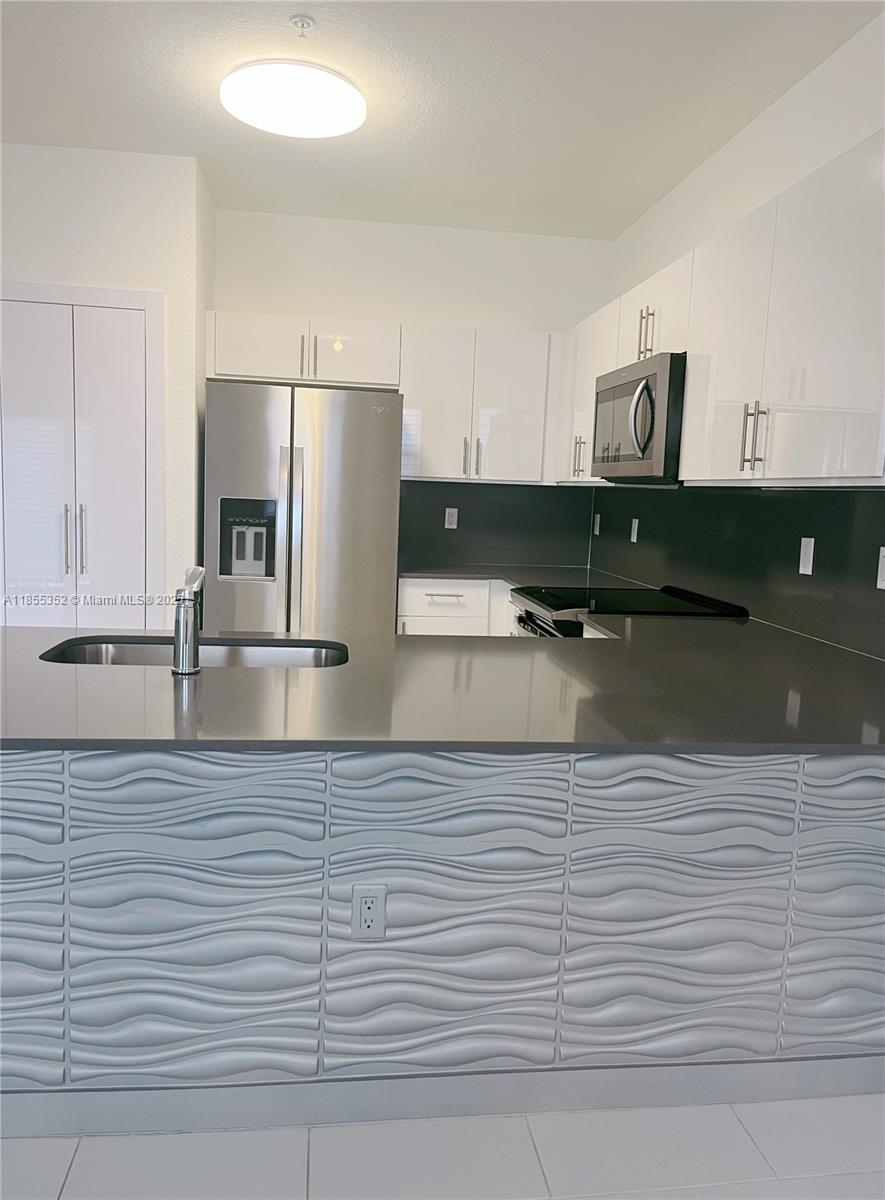 15650 Southwest 136th Street, Unit 218 Miami, FL 33196 - Photo 4 of 25 a kitchen with stainless steel appliances granite countertop a sink and cabinets