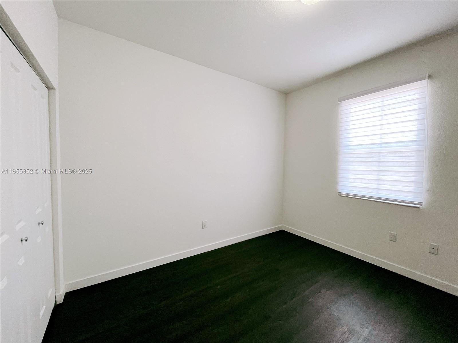 15650 Southwest 136th Street, Unit 218 Miami, FL 33196 - Photo 7 of 25 a view of an empty room with wooden floor and a window