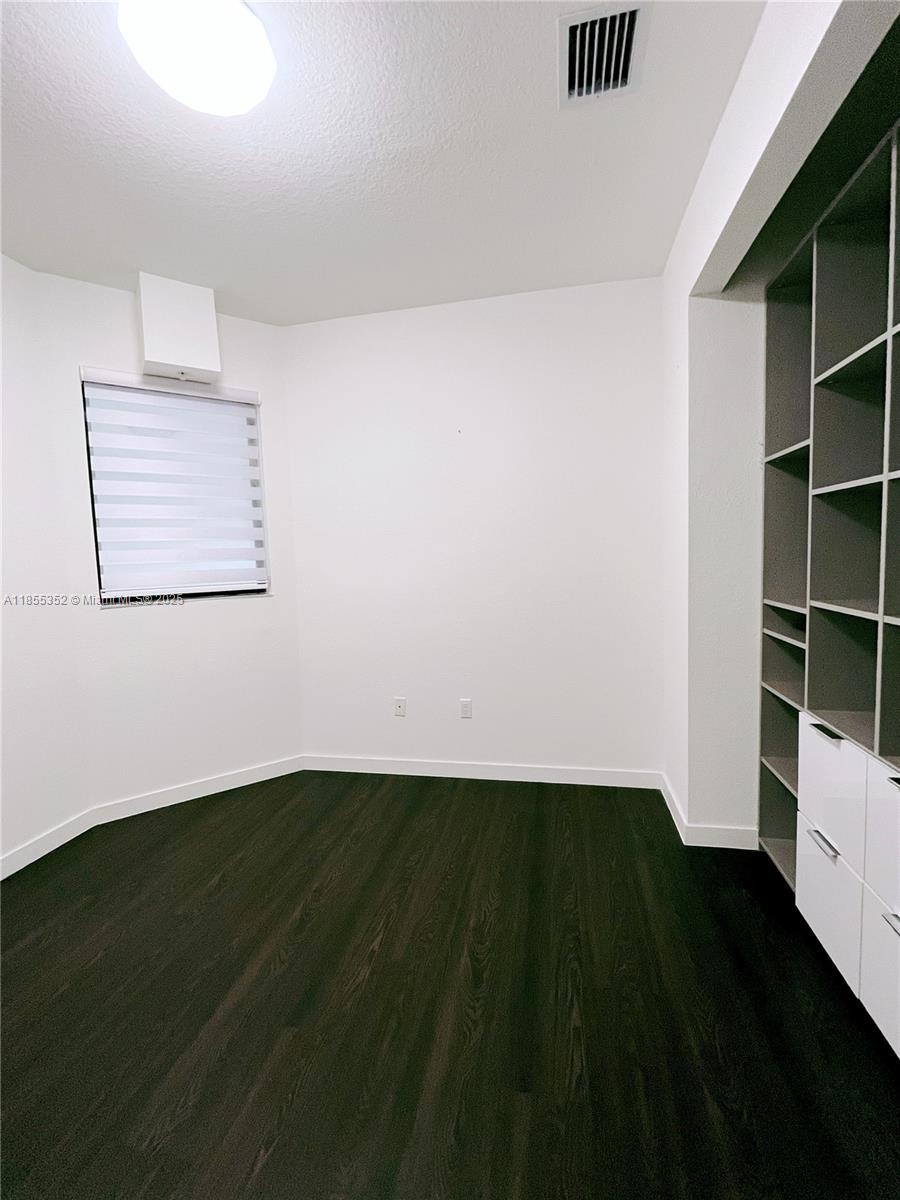 15650 Southwest 136th Street, Unit 218 Miami, FL 33196 - Photo 10 of 25 a view of an empty room with wooden floor and a window