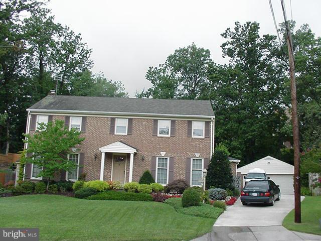 a front view of a house with a garden and trees