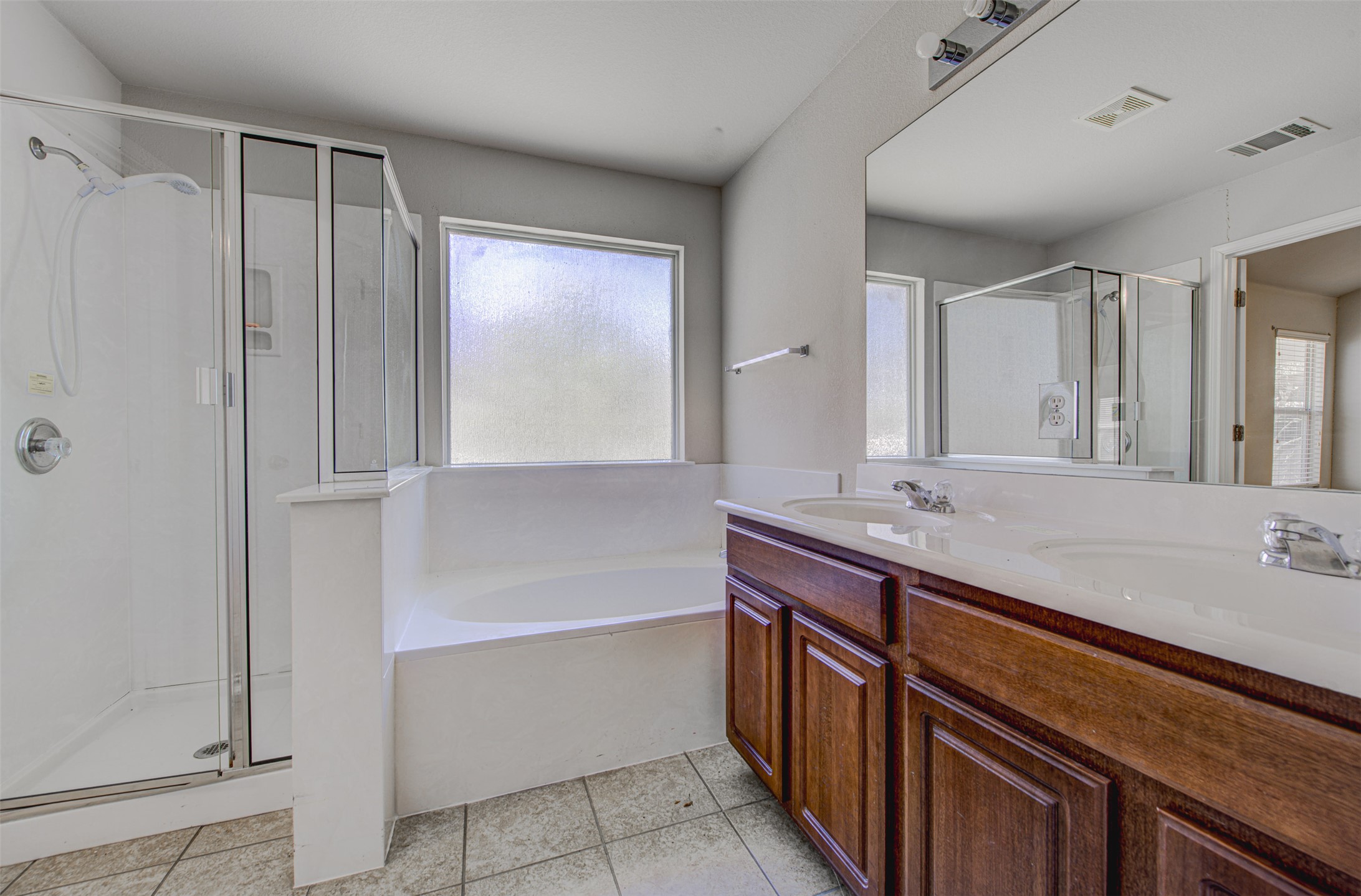 2090 Intrepid Drive Buda, TX 78610 - Photo 12 of 24 Bathroom featuring double vanity, a stall shower, a garden tub, and light tile patterned flooring