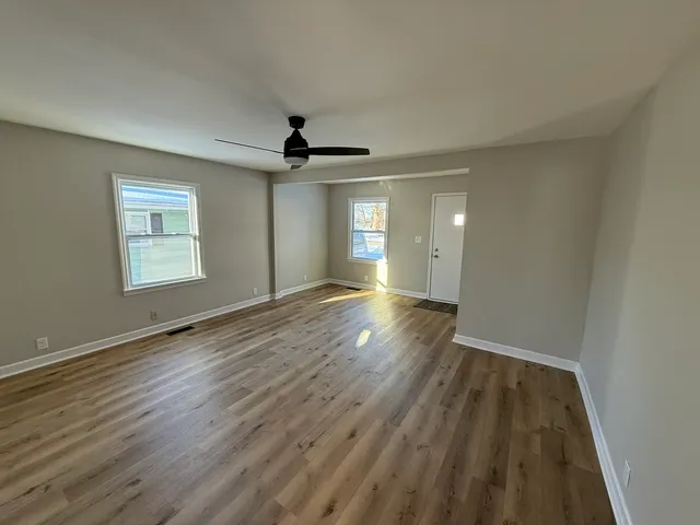 a view of empty room with wooden floor and fan