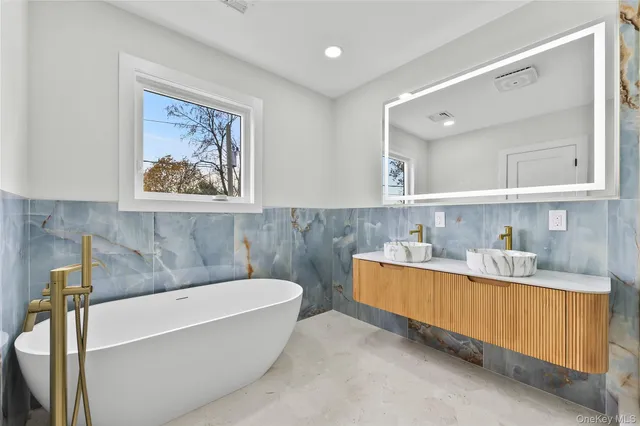 a bathroom with a tub a sink and mirror