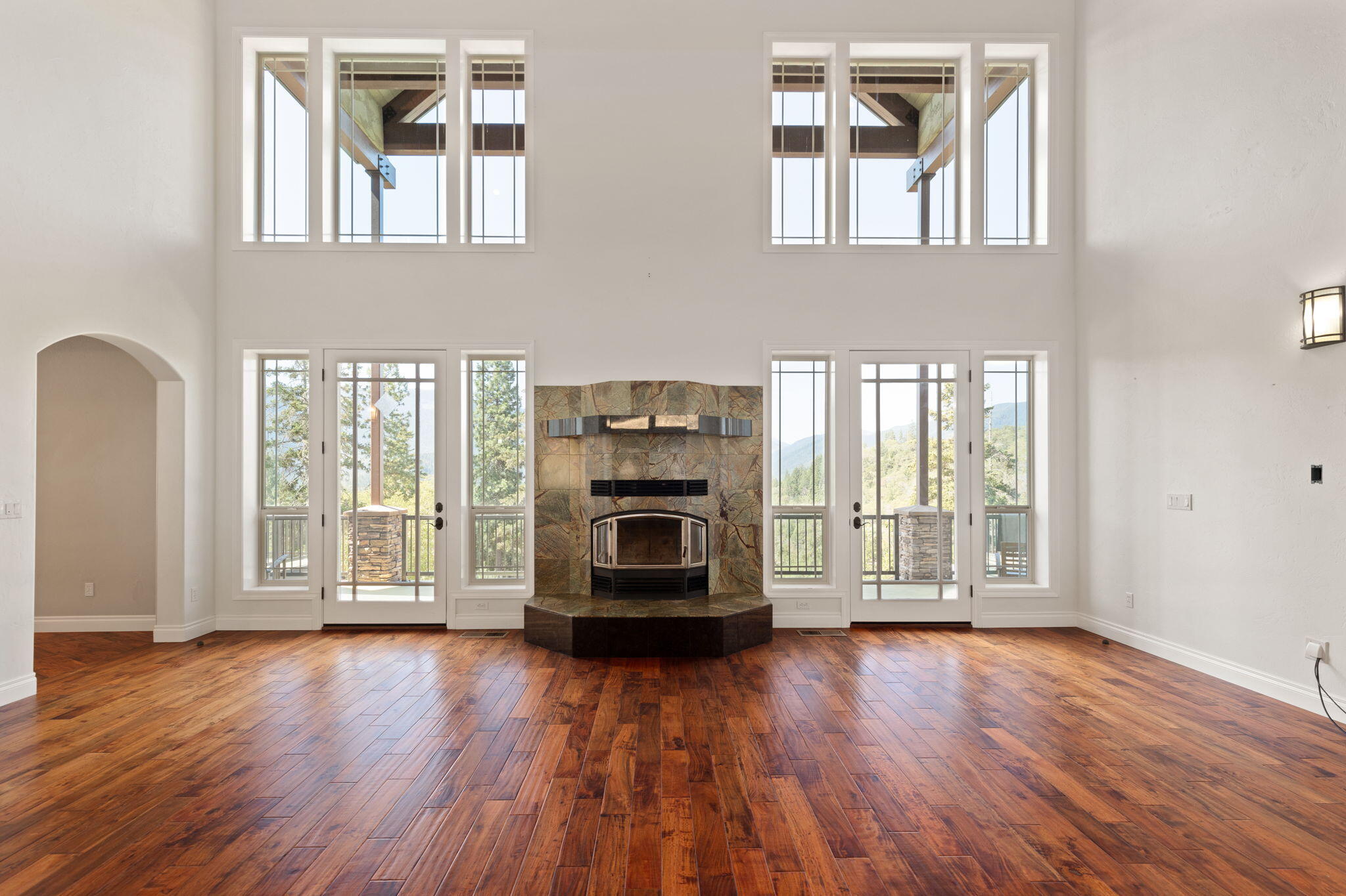 7304 North Applegate Road Grants Pass, OR 97527 - Photo 19 of 87 an empty room with wooden floor fire place and windows
