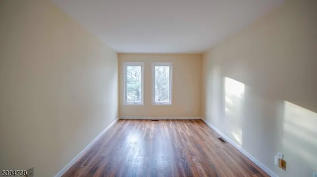 a view of an empty room with wooden floor and window