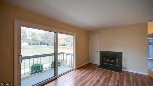 a view of empty room with wooden floor and fireplace