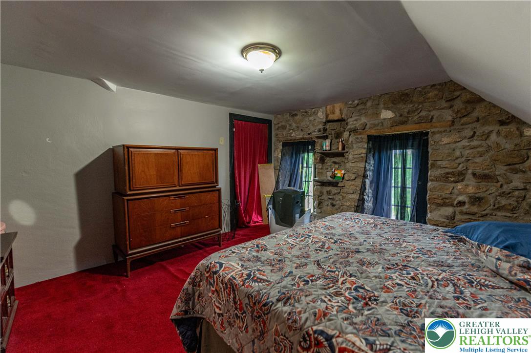 2485 Hieter Road Quakertown, PA 18951 - Photo 55 of 97 A cozy bedroom with distinctive exposed stone walls and vibrant red carpeting.