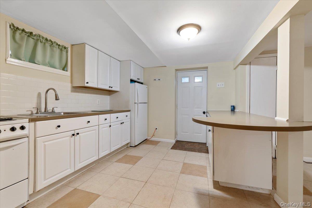 212 Locust Drive Rocky Point, NY 11778 - Photo 27 of 38 a kitchen with white cabinets and sink