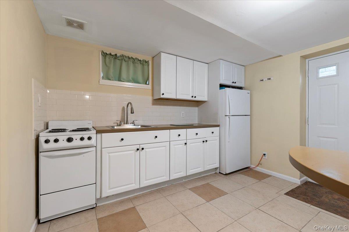 212 Locust Drive Rocky Point, NY 11778 - Photo 28 of 38 a kitchen with white cabinets and white appliances