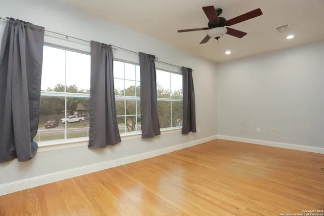 an empty room with wooden floor and windows