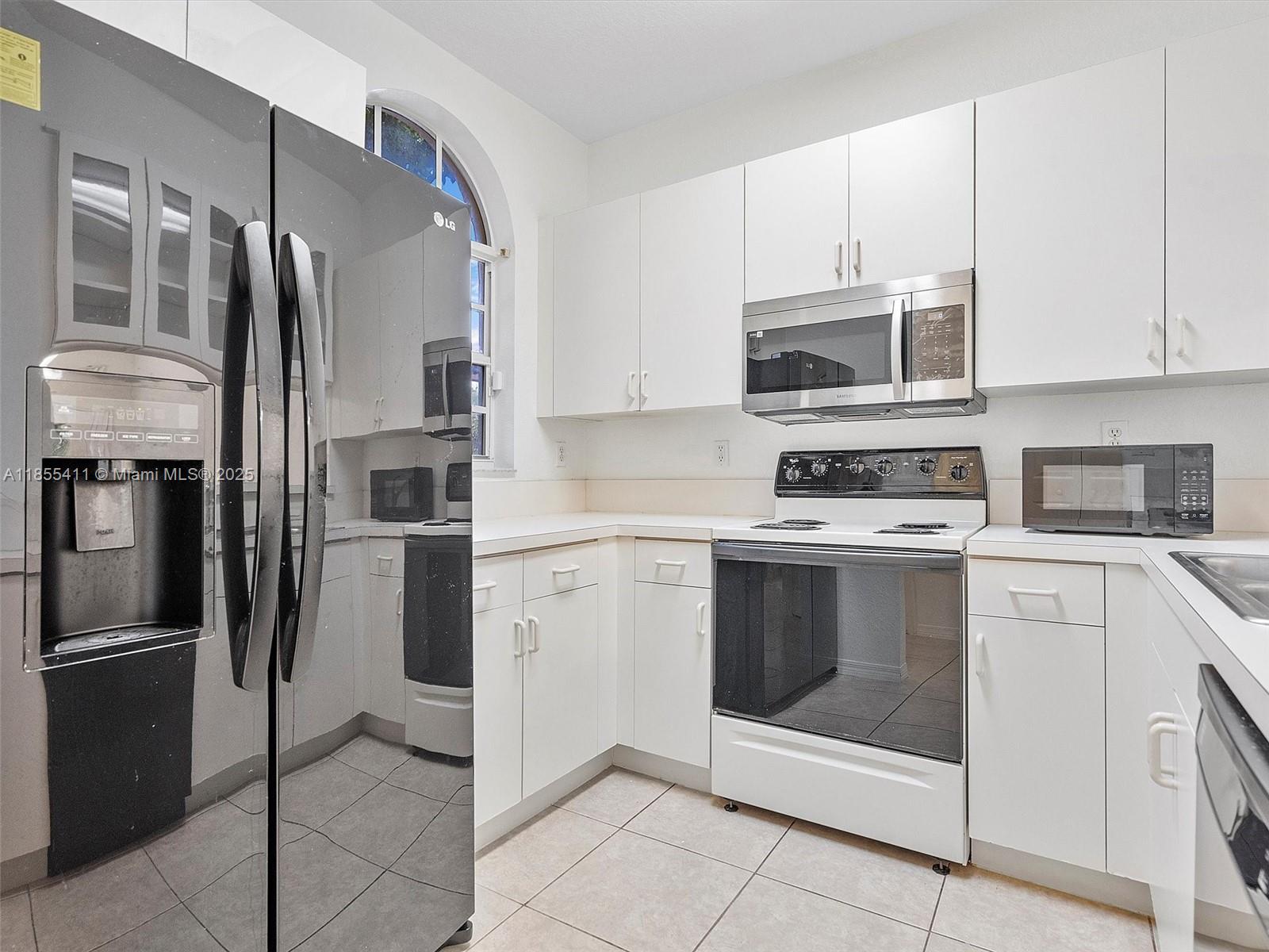 4964 Southwest 128th Avenue Miramar, FL 33027 - Photo 11 of 38 a kitchen with stainless steel appliances a stove a microwave and a refrigerator