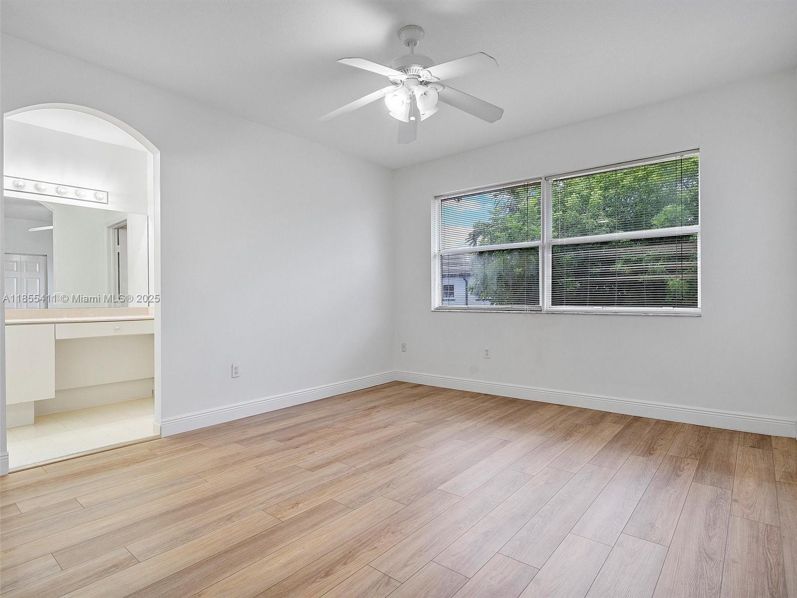 4964 Southwest 128th Avenue Miramar, FL 33027 - Photo 16 of 38 an empty room with wooden floor chandelier fan and windows