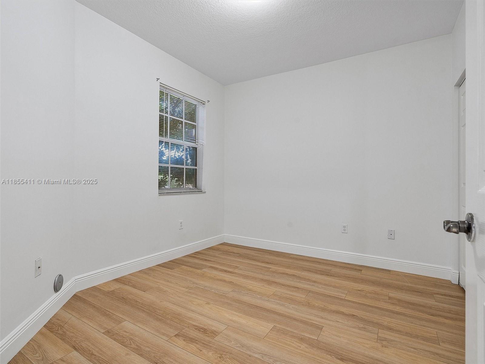 4964 Southwest 128th Avenue Miramar, FL 33027 - Photo 26 of 38 an empty room with wooden floor and windows
