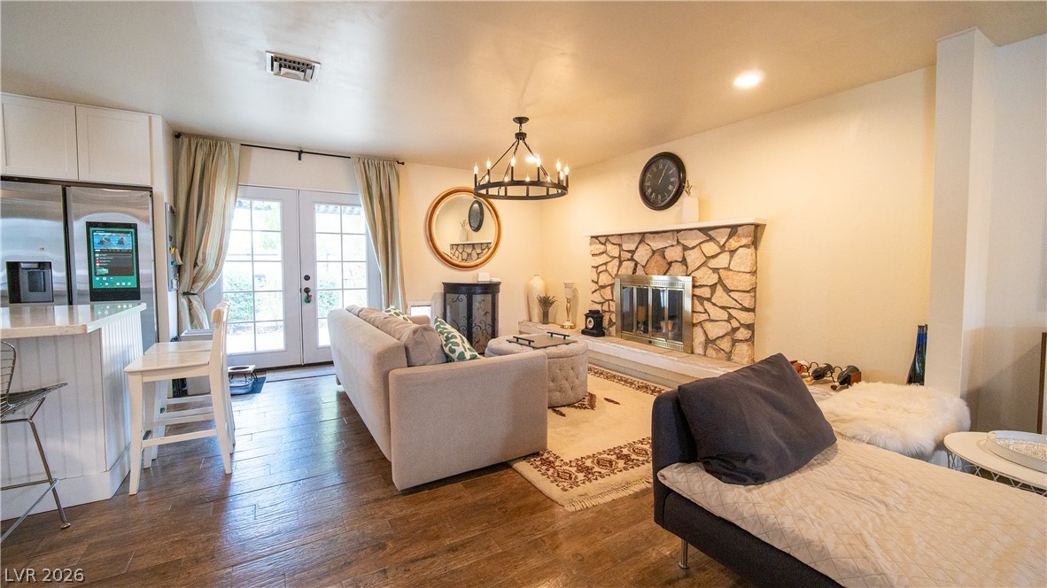 425 Blackridge Road Henderson, NV 89015 - Photo 9 of 31 A stone fireplace anchors this living space accented by wood flooring and French doors.