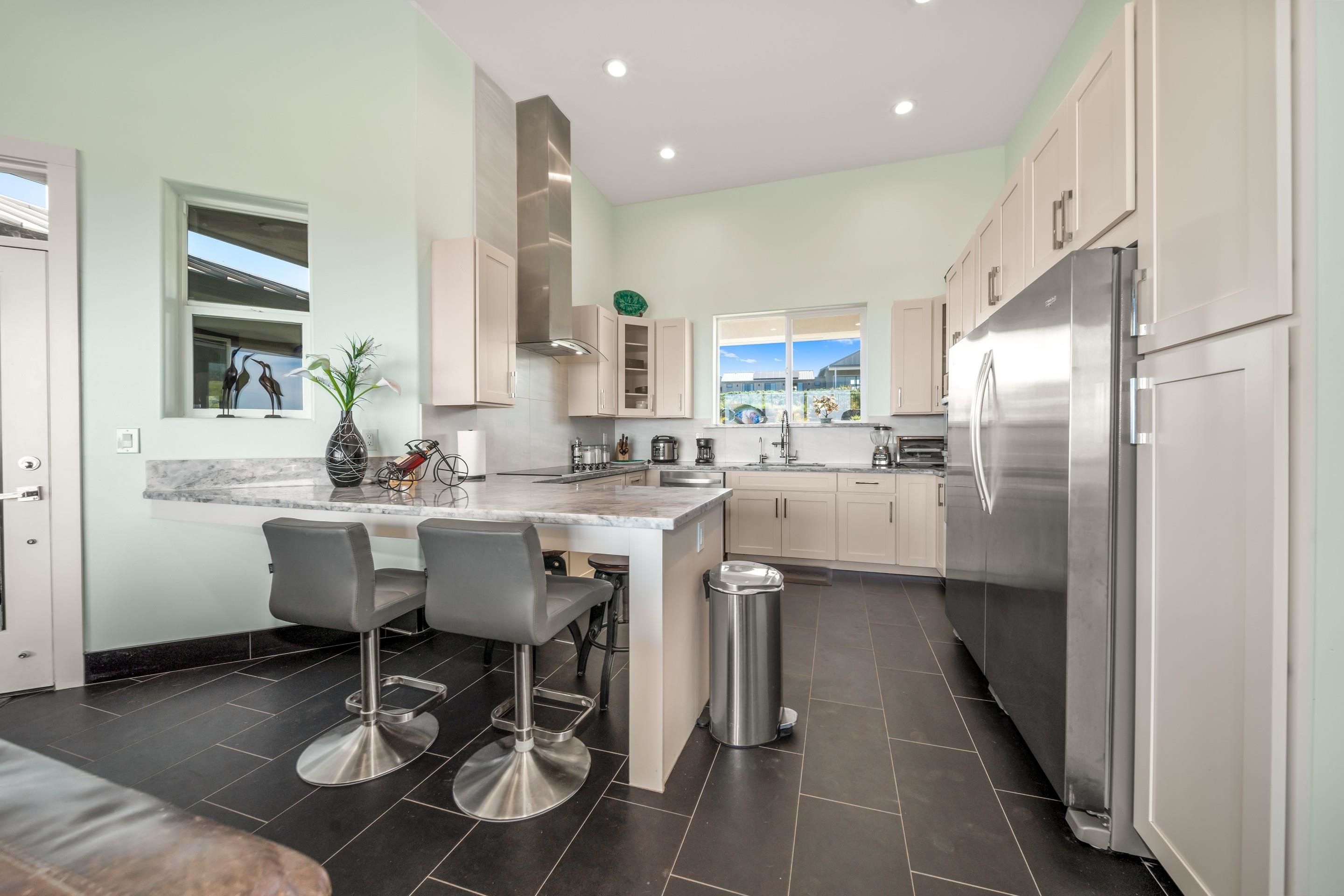 272 Huahua Street Kula, HI 96790 - Photo 13 of 43 a kitchen with stainless steel appliances kitchen island granite countertop a sink and cabinets